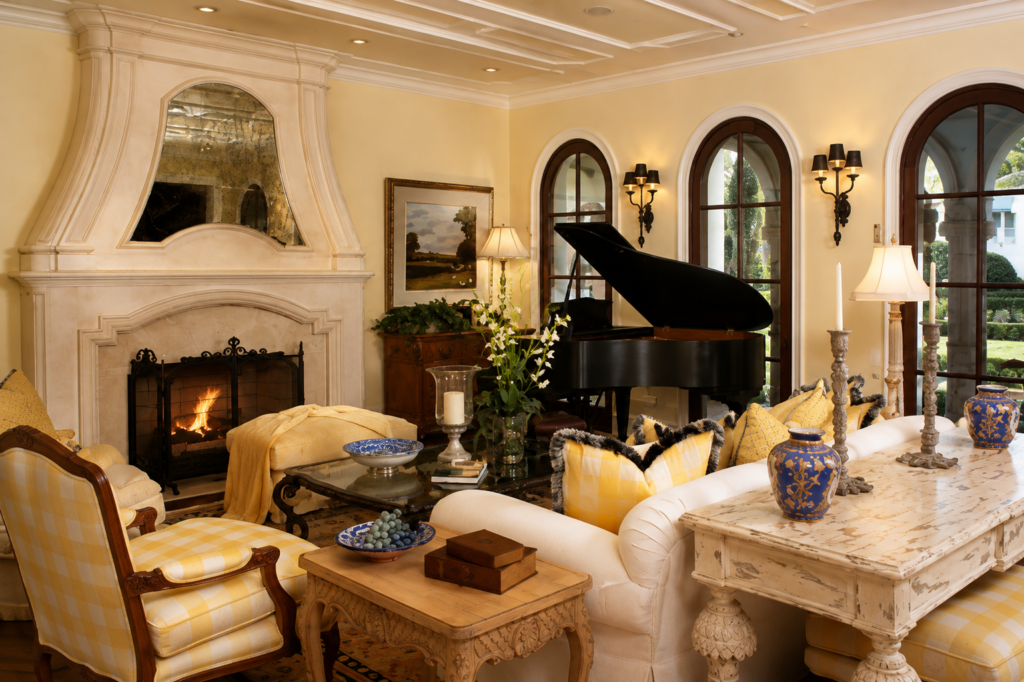 Italianate formal living room with grand piano, stone fireplace, arched windows, and coffered ceiling by Posada Custom Homes in Orlando, FL