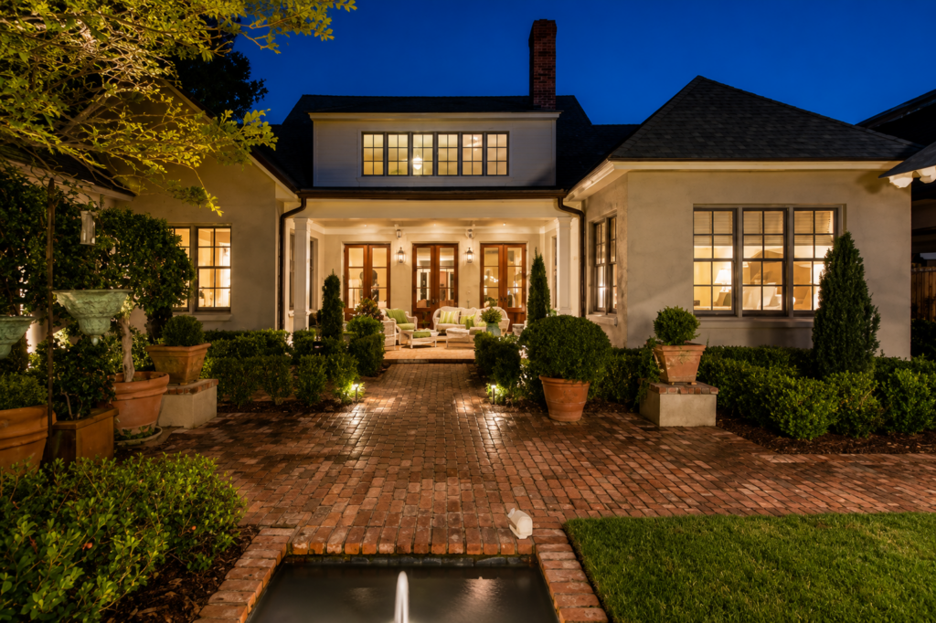 Urban Life Low Country rear courtyard at night with brick walkway and water fountain by Posada Custom Homes in Orlando, FL