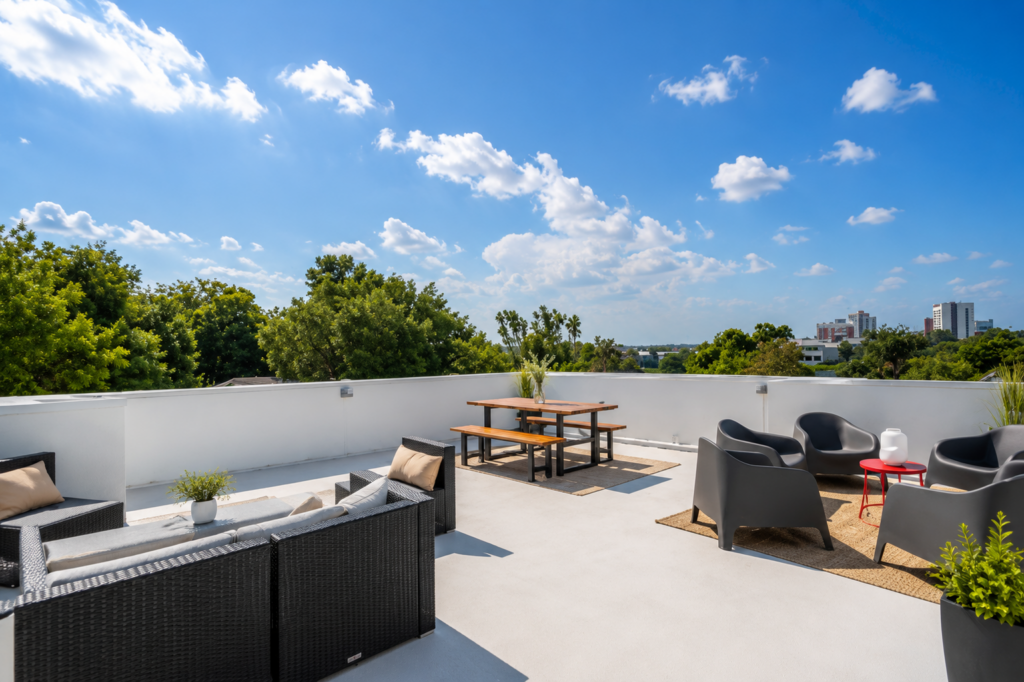 Urban Life rooftop terrace with outdoor lounge seating, dining area, and city skyline views by Posada Custom Homes in Orlando, FL