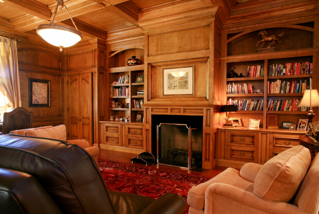 Study with maple wood paneling, built-in bookshelves, a fireplace, and a coffered wood ceiling