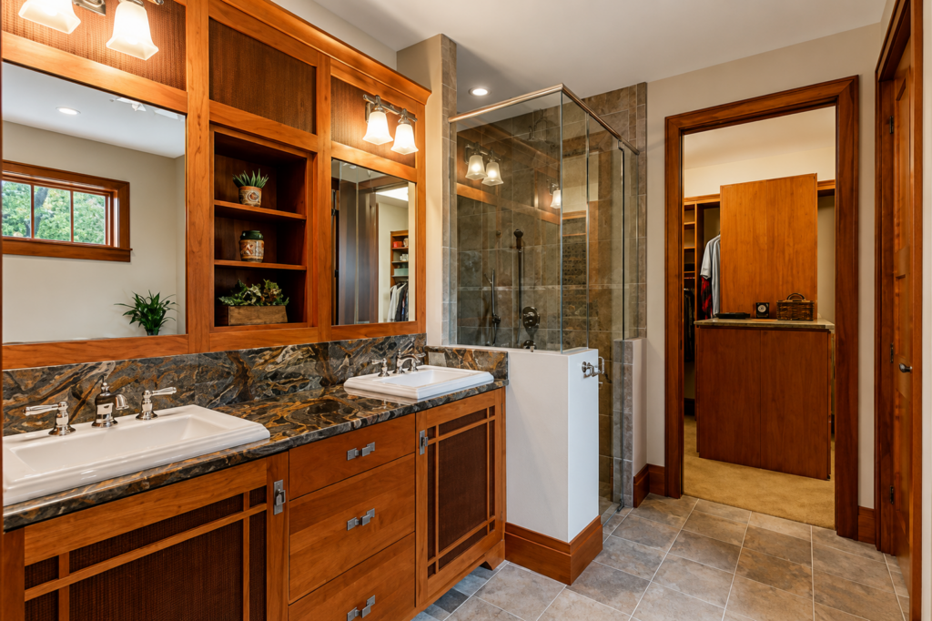 Primary bathroom with a dual vanity, stone tile, and a glass-enclosed shower