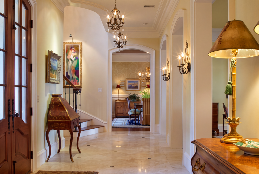 Foyer with a stone floor, iron chandelier, and an arched opening looking through to the dining room