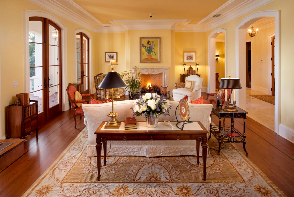 Living room with a fireplace, arched French doors, hardwood floors, and painted trim