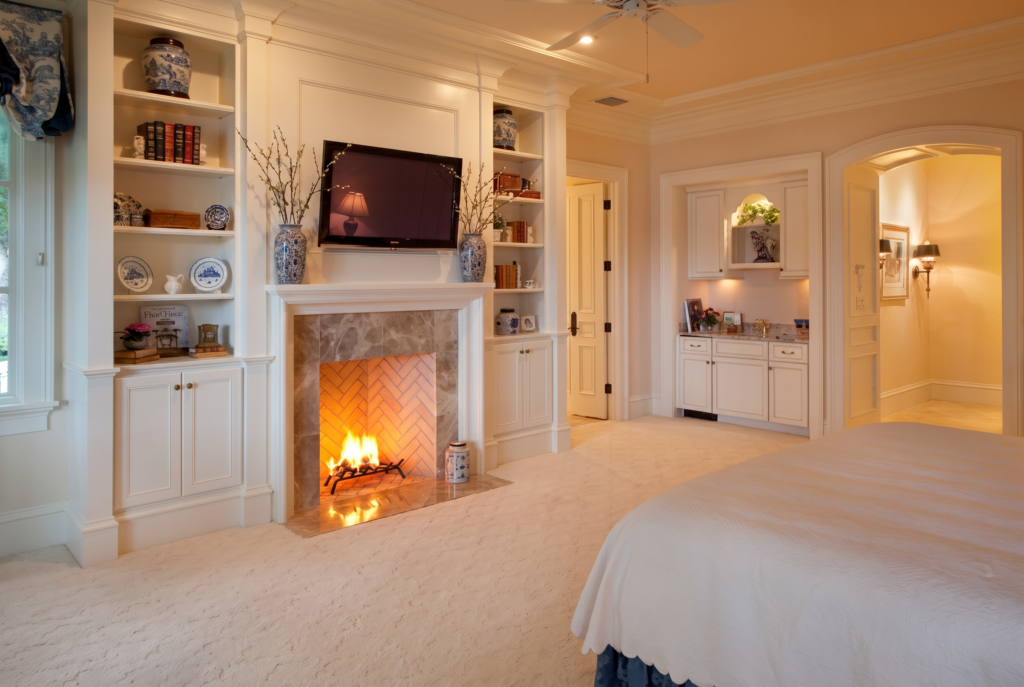 Primary bedroom with a fireplace flanked by built-in shelving and a wall-mounted television