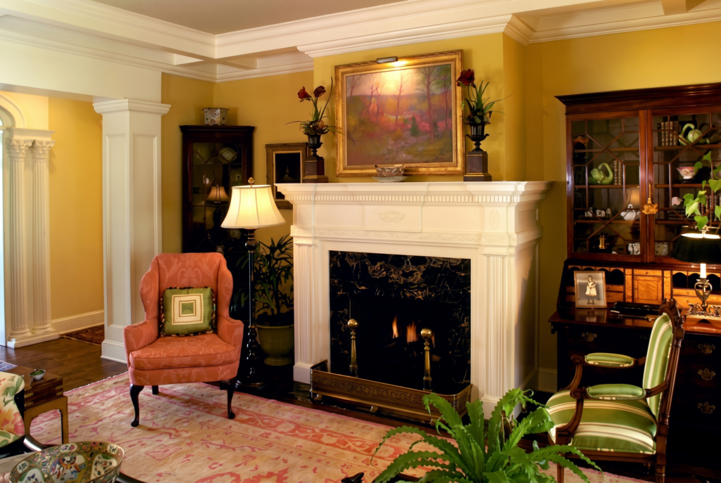 Living room with a carved wood mantel, black marble fireplace surround, fluted pilasters, and dentil crown molding