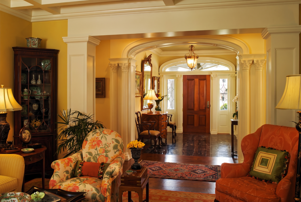 Entry hall seen from the living room, with an arched opening on fluted columns and a mahogany door with sidelights