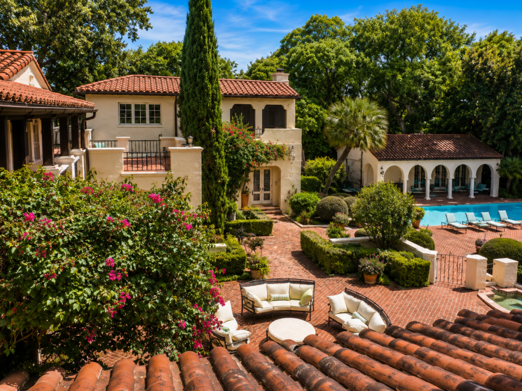 Rear elevation with a brick terrace, arched loggia, wrought iron balconies, and bougainvillea climbing the stucco